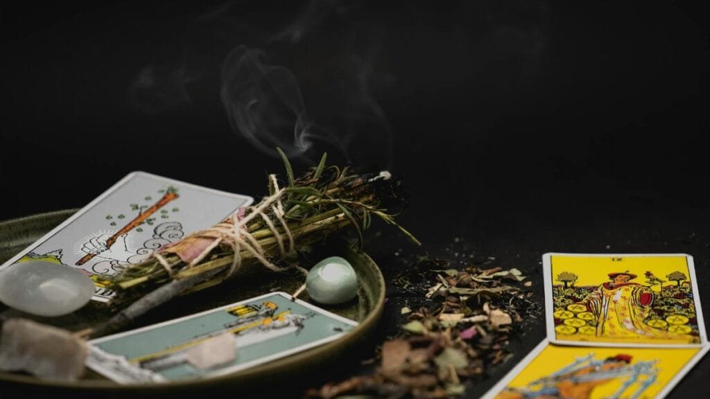 A spiritual still life with tarot cards, herbs, and crystals on a dark surface for meditation.