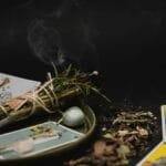 A spiritual still life with tarot cards, herbs, and crystals on a dark surface for meditation.