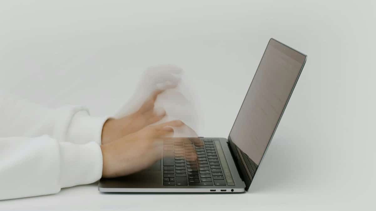 Hands rapidly typing on a laptop, illustrating speed and technology in a digital work environment.
