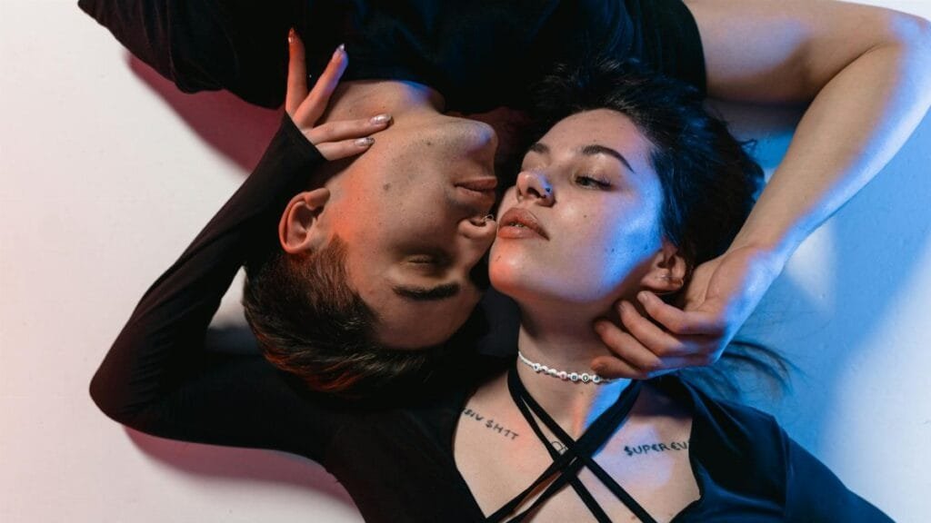A creative, intimate portrait of a young couple embracing under neon lighting.