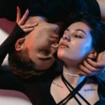 A creative, intimate portrait of a young couple embracing under neon lighting.