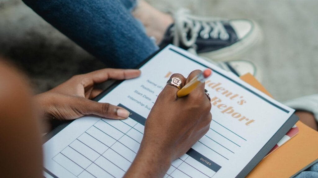 A student diligently writes on a report form outdoors while focusing on the task.