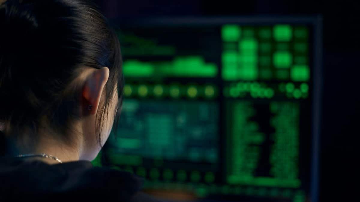 A woman focuses on data displayed on a computer screen in a dark room.
