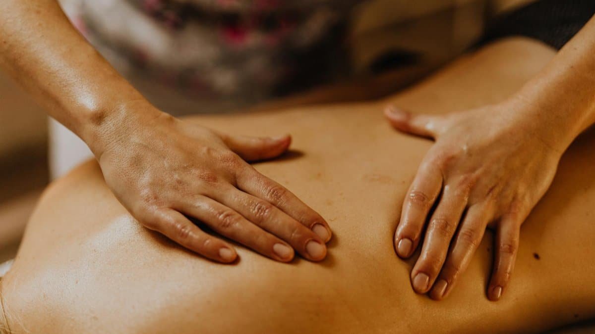Close-up of hands giving a soothing back massage in a calm setting.