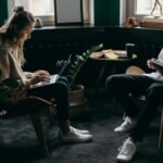 Two young adults working in a stylish home office, using laptops and tablets for remote work.
