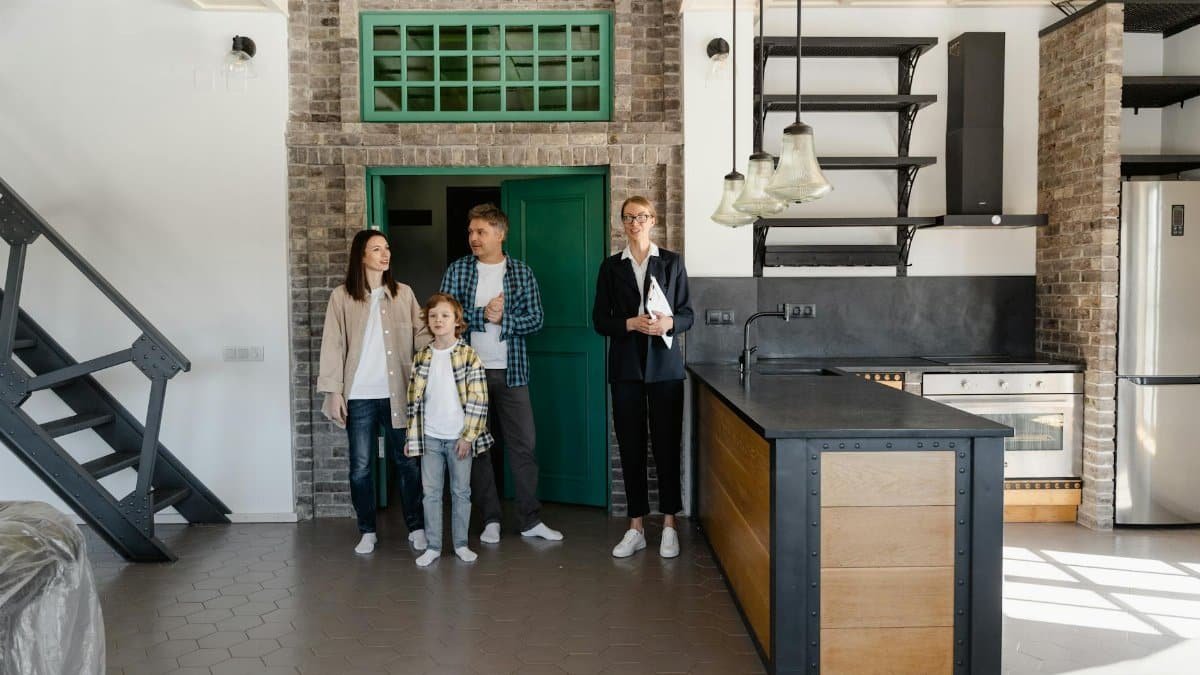 A family with a realtor viewing a modern industrial-style kitchen in a new home.