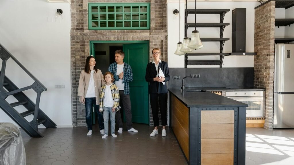 A family with a realtor viewing a modern industrial-style kitchen in a new home.
