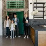 A family with a realtor viewing a modern industrial-style kitchen in a new home.