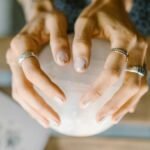 Hands wearing rings holding a crystal sphere, symbolizing spirituality and healing.