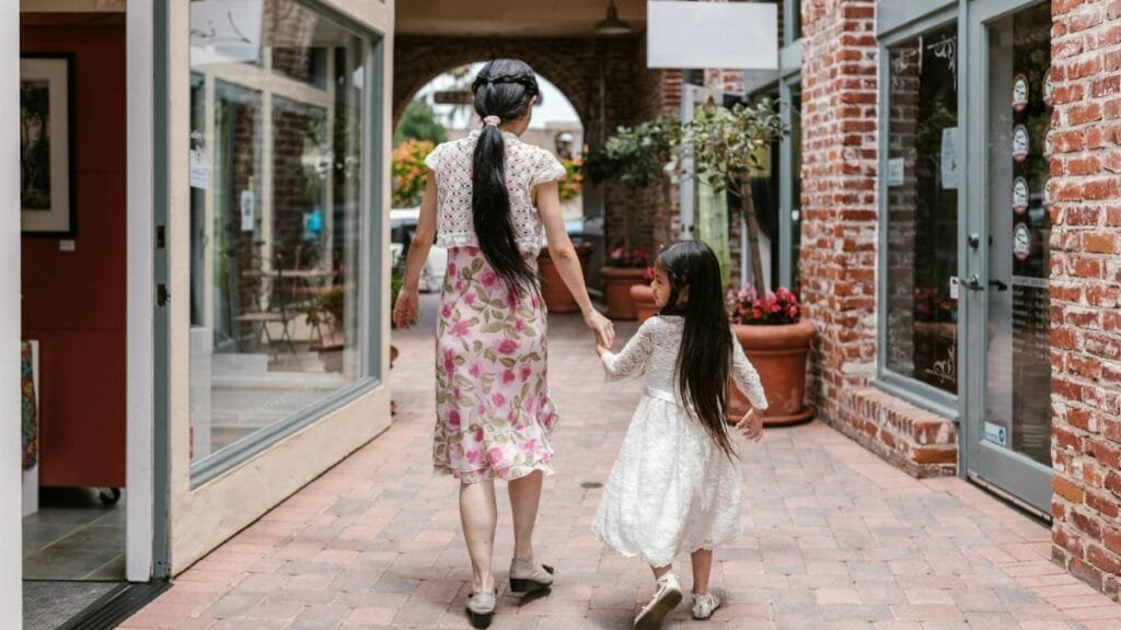 A woman and child walk hand in hand through a charming brick alley, creating a heartwarming family scene.