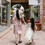 A woman and child walk hand in hand through a charming brick alley, creating a heartwarming family scene.
