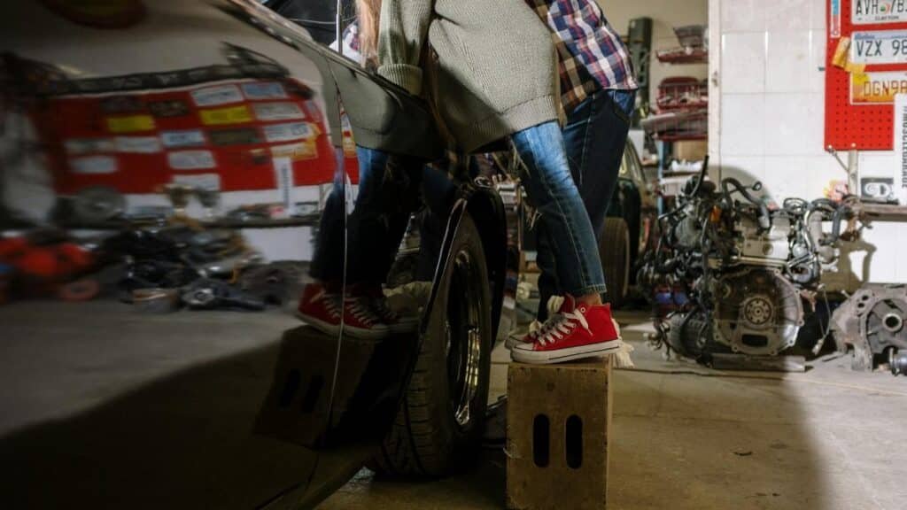 A father and daughter bonding while working on a car in a repair shop, showcasing teamwork and family.