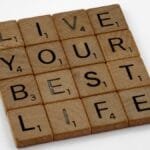 Scrabble tiles arranged to spell 'Live Your Best Life' on a white background.