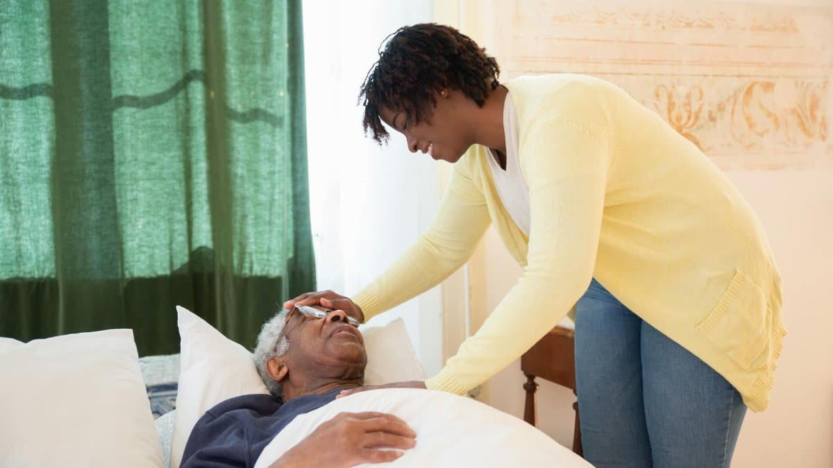 A loving daughter tends to her elderly father at home, offering comfort and care.