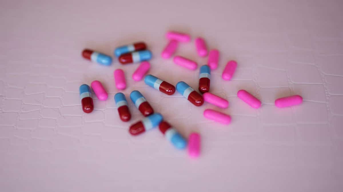 Vibrant pink and blue capsules scattered on a light textured background.