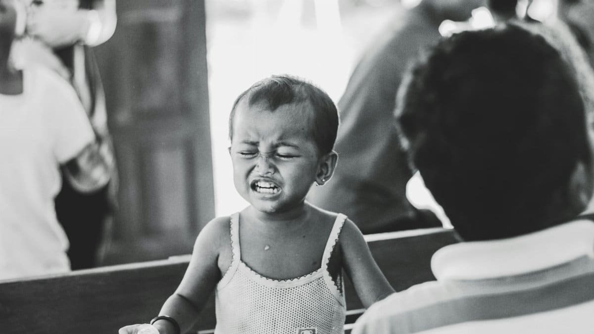 A black and white photo of a young child outdoors with a strong facial expression.