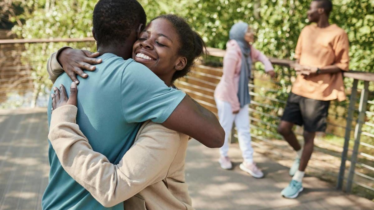 Joyful friends share a heartfelt embrace outdoors on a sunny day.