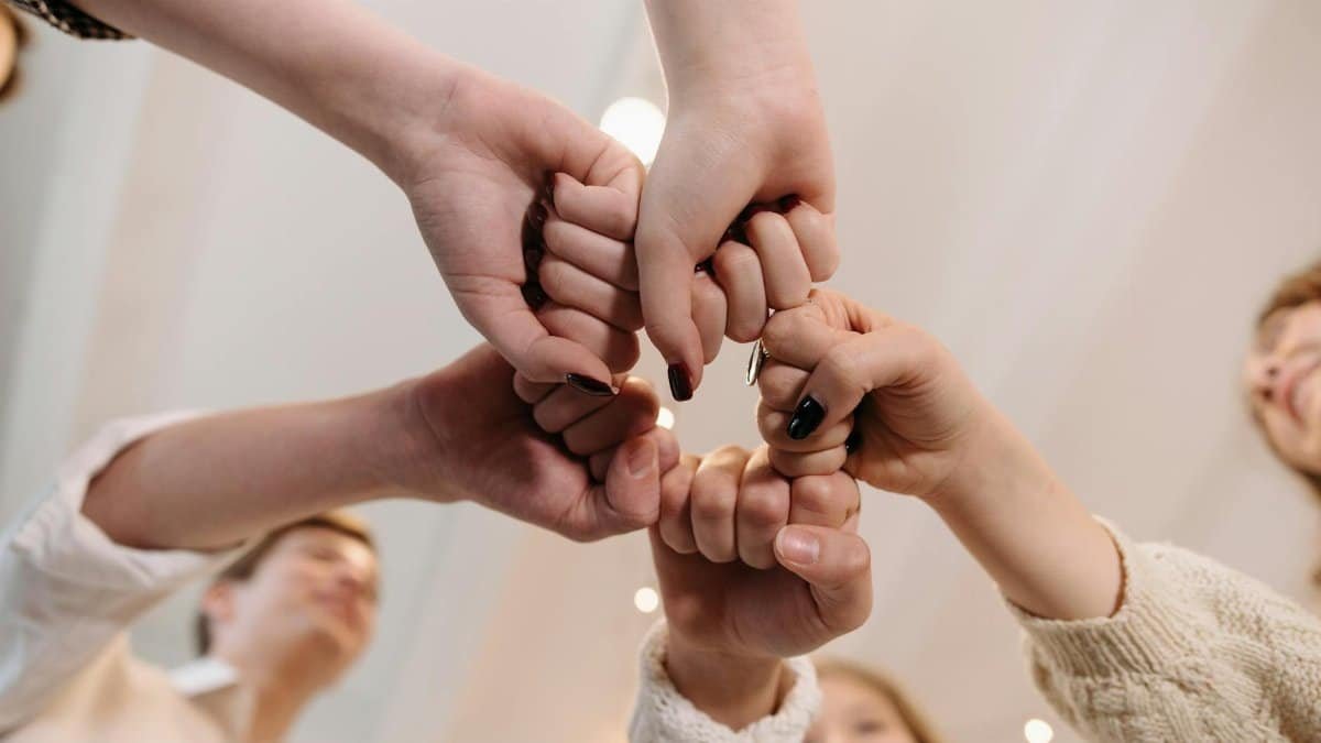 Close-up of a diverse group joining fists in a show of unity and teamwork indoors.