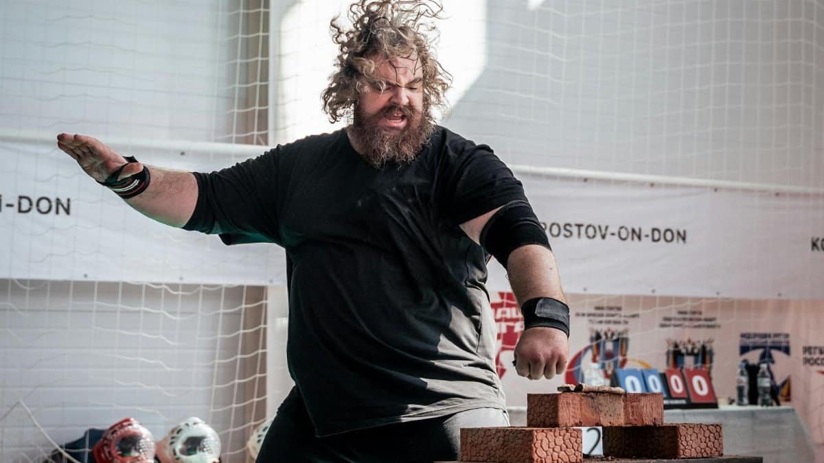 Dynamic image of a martial artist breaking bricks indoors, showcasing strength and skill.