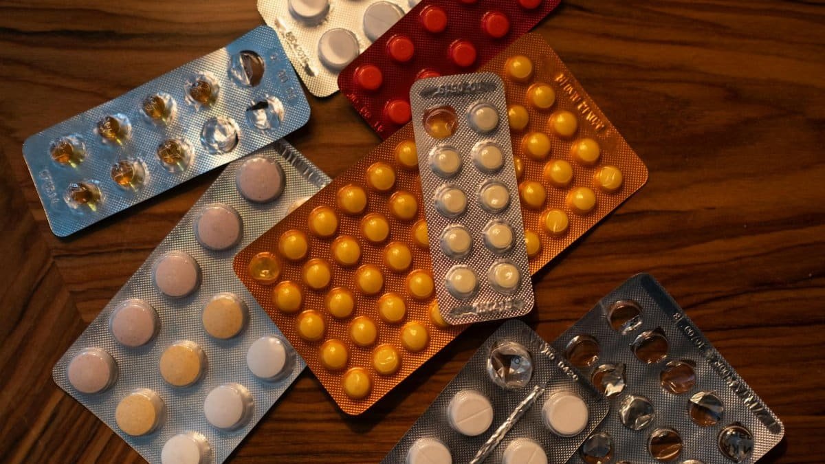 Colorful blister packs of medicine pills on a wooden surface, viewed from above.