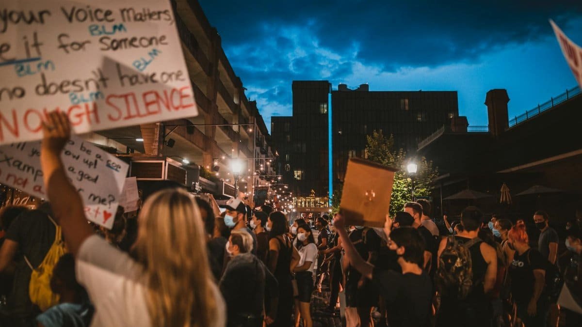Side view group of unrecognizable diverse activists with posters protesting for Black Lives Matter movement on street in evening