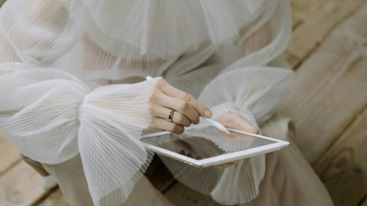 A woman in a stylish blouse holds a tablet and stylus, blending technology with elegance.