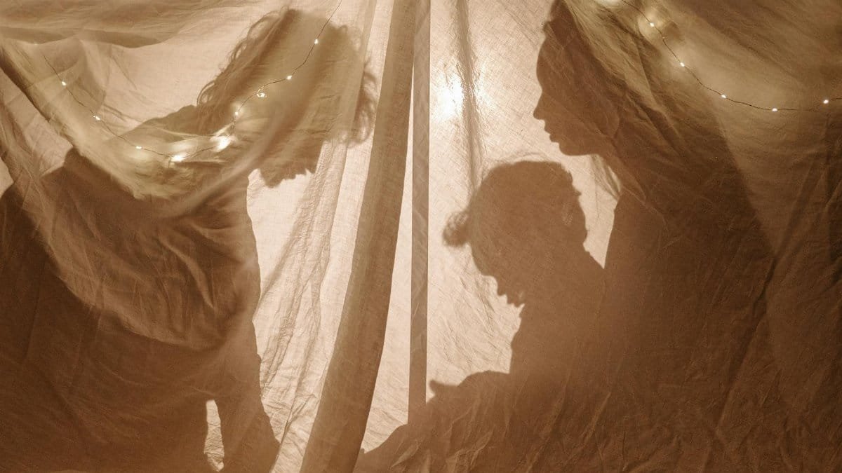 Silhouettes of a family playing inside a decorated tent with soft lights.