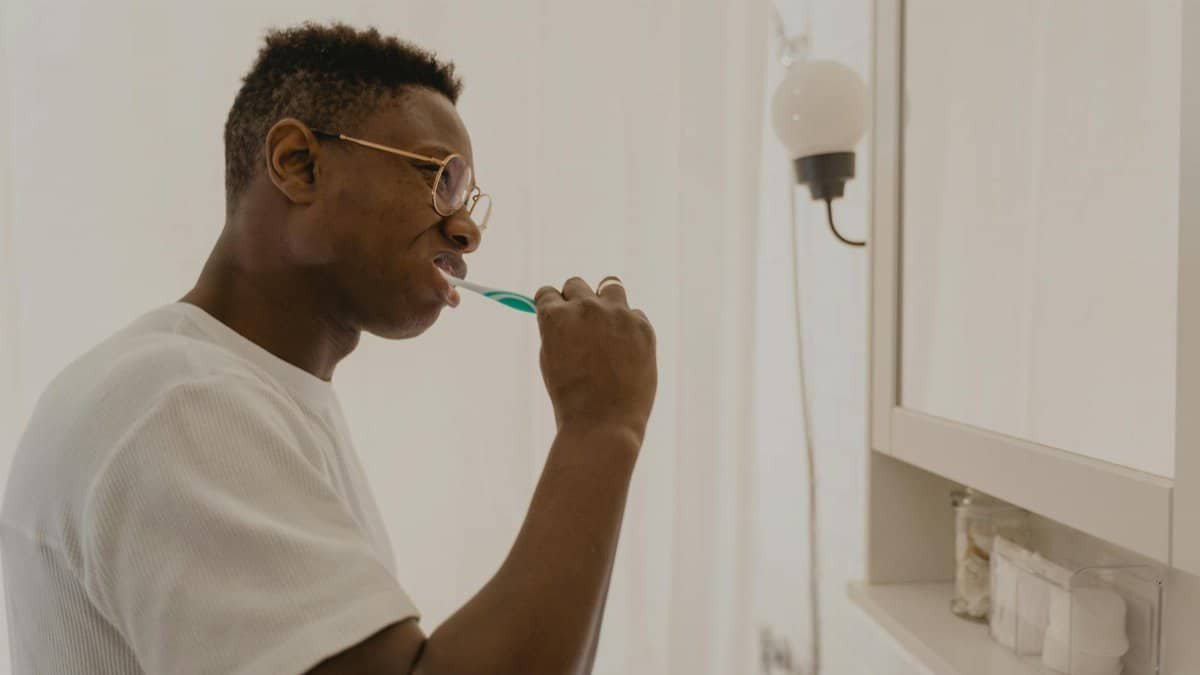 Man brushing his teeth in a bathroom, focusing on daily oral care and hygiene.
