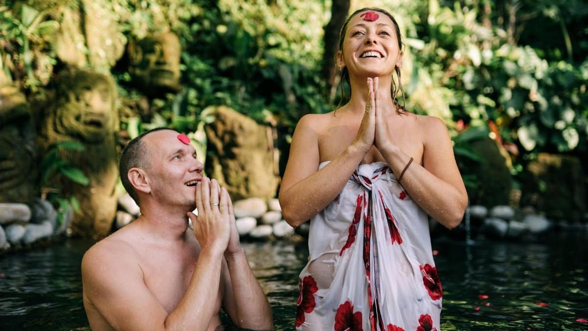 Happy couple enjoying a spiritual water ritual in a lush tropical environment, radiating joy and peace.