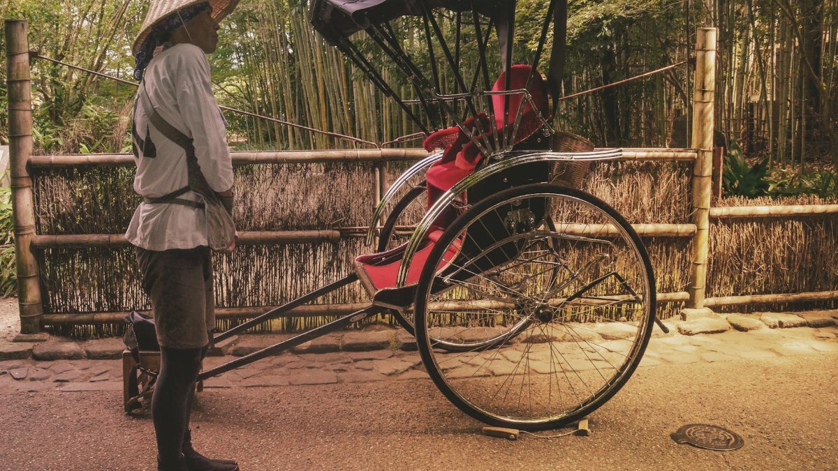 Rickshaw puller waiting on a scenic path in Kyoto, Japan, showcasing traditional culture.