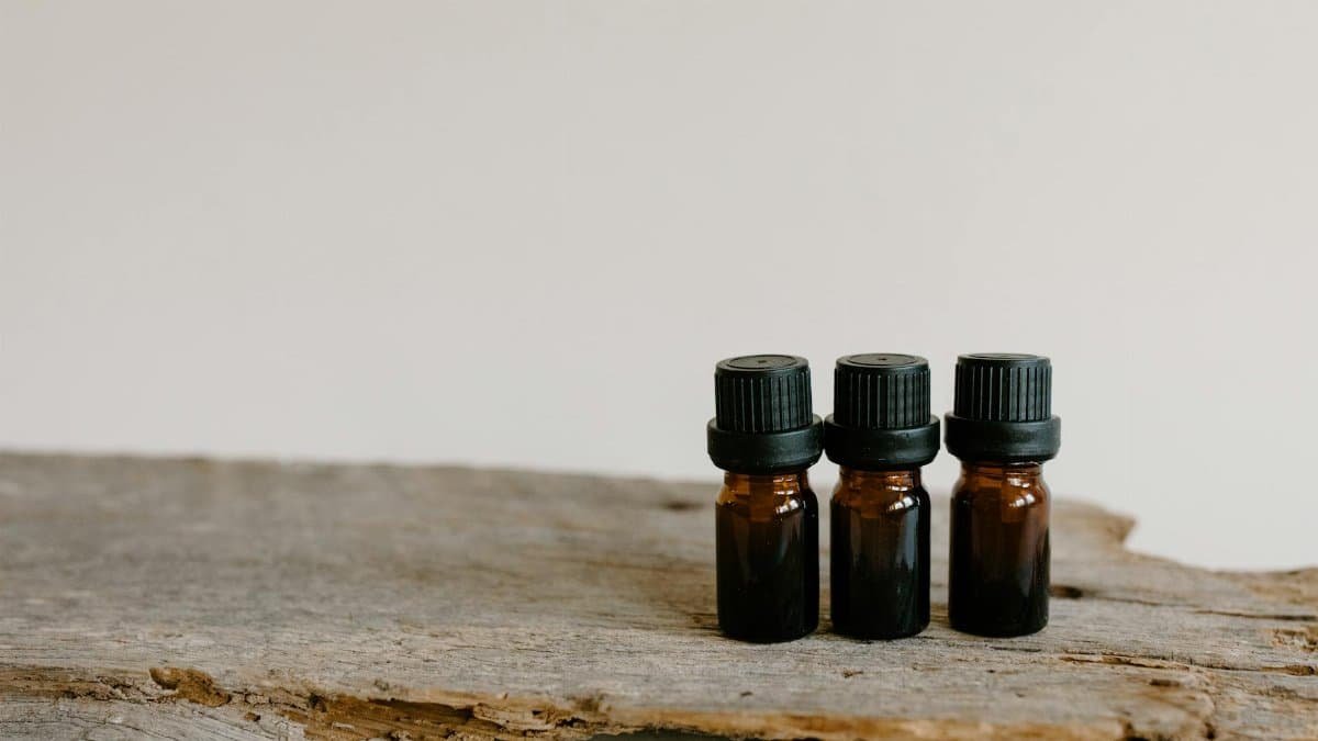 Three essential oil bottles on rustic wood surface, perfect for aromatherapy and natural healing themes.