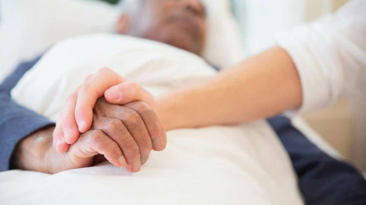 A comforting gesture as a hand holds another in a hospital setting, symbolizing care and support.
