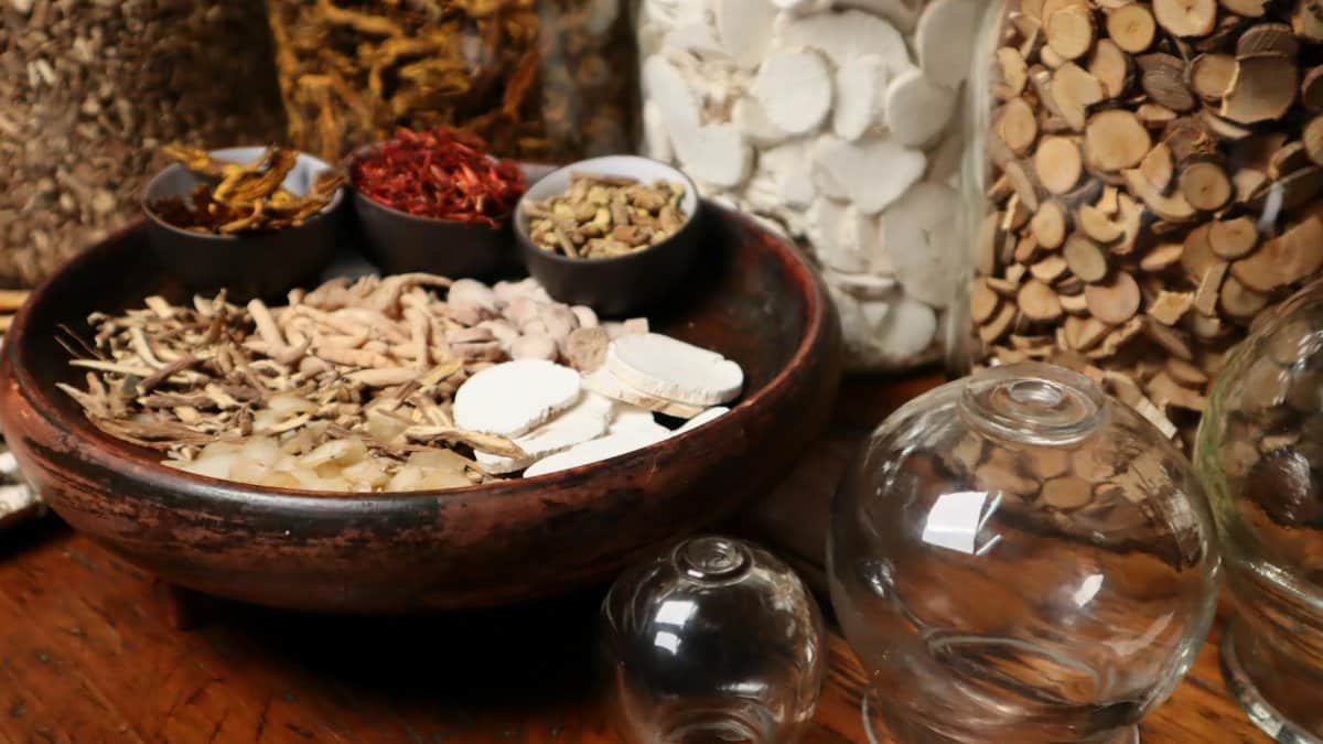 Close-up of herbal ingredients and glass jars used in traditional Chinese medicine therapy.