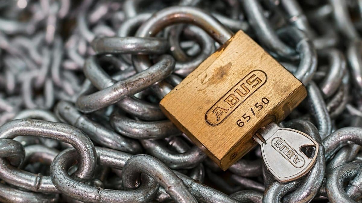 A detailed macro shot of a brass padlock with a key on heavy steel chains, symbolizing security and protection.