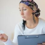 Woman with headscarf in bedroom reviews medication, symbolizing hope and recovery.