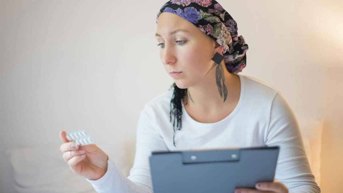Woman with headscarf in bedroom reviews medication, symbolizing hope and recovery.