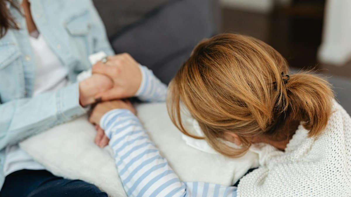 Two women share a comforting moment, emphasizing support and empathy in emotional distress.