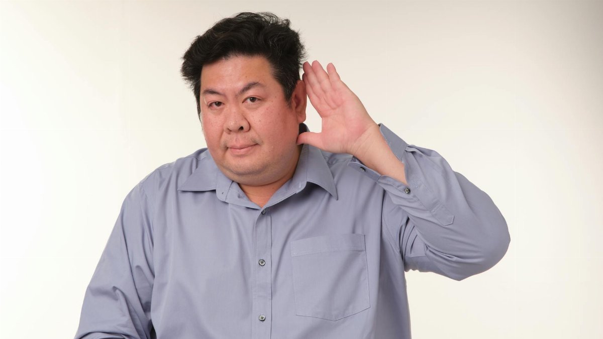 A man in a pose demonstrating the gesture of listening in a studio setting.