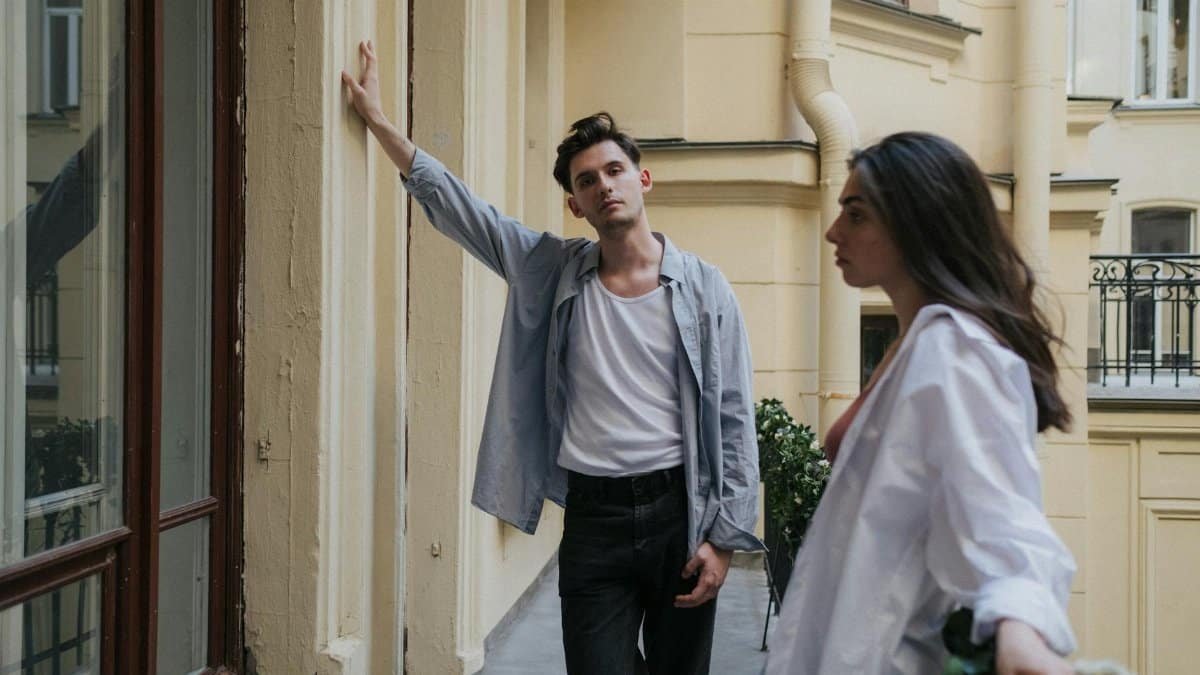 A stylish couple stands on a city balcony, showcasing modern urban living and fashion vibes.