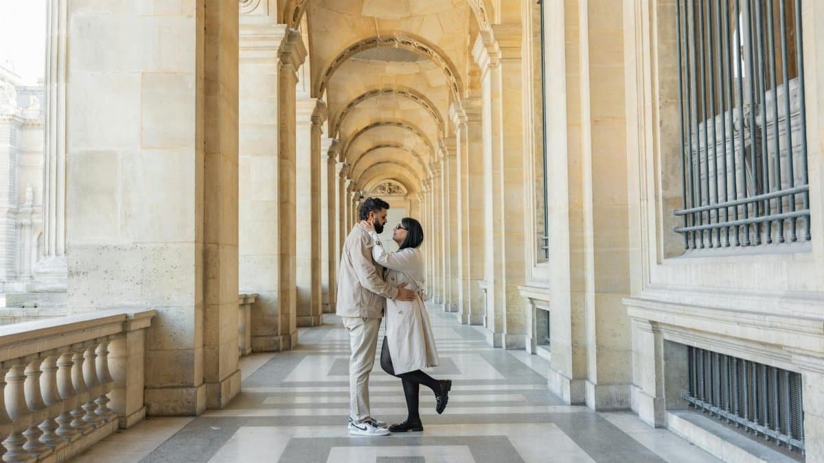 Couple embracing in a grand architectural corridor, showcasing love and intimacy.