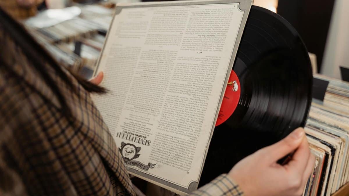 Close-up of a person holding and browsing vinyl records in a nostalgic music store.
