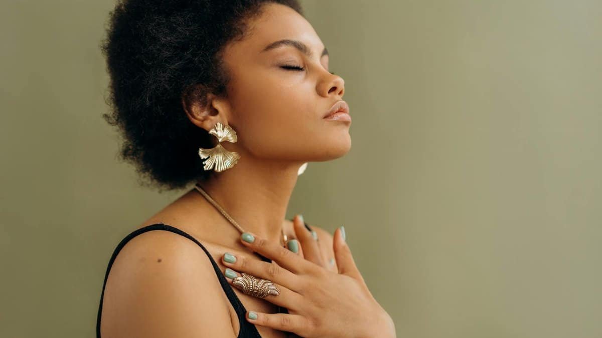 Close-up of a woman with afro hair meditating, eyes closed, embracing wellness and mindfulness.
