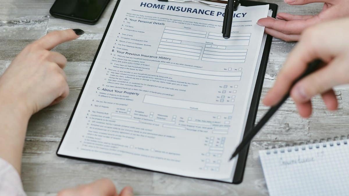 Three individuals collaborating on a home insurance policy document. Elements include a clipboard, notes, and pointing hands.