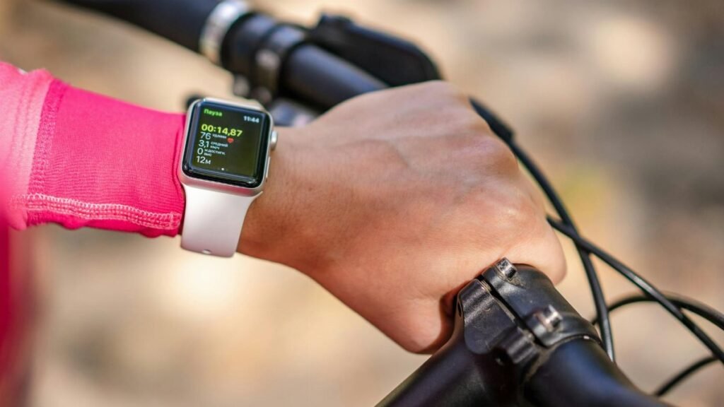 Cyclist checks smartwatch during bike ride. Focus on technology and fitness tracking.