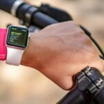 Cyclist checks smartwatch during bike ride. Focus on technology and fitness tracking.