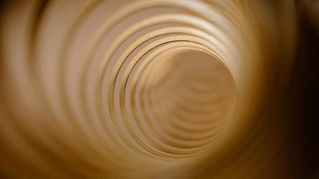 Abstract view of concentric circles forming a tunnel-like vortex in warm tones.