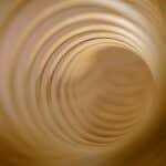 Abstract view of concentric circles forming a tunnel-like vortex in warm tones.