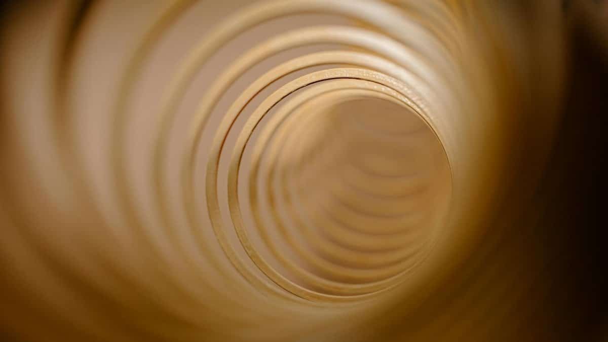Abstract view of concentric circles forming a tunnel-like vortex in warm tones.