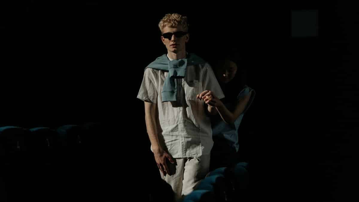 A visually impaired man with guide navigating through a dark movie theater.