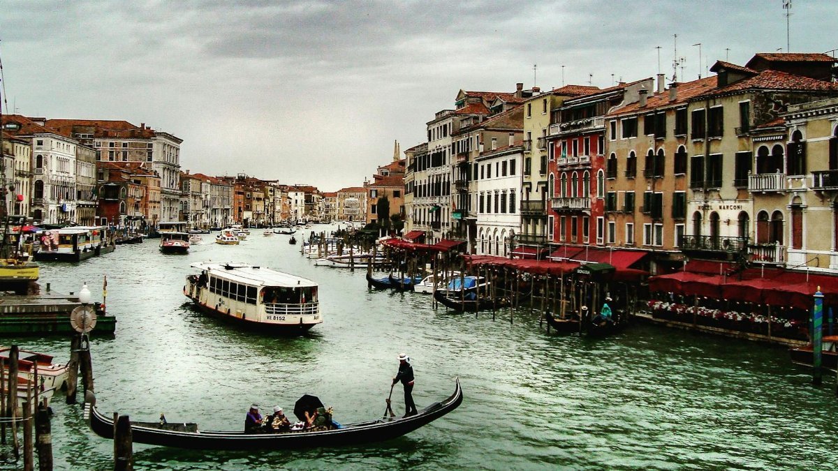 Idyllic scene of gondolas and boats on the Grand Canal in Venice, Italy with historic buildings lining the waterfront.